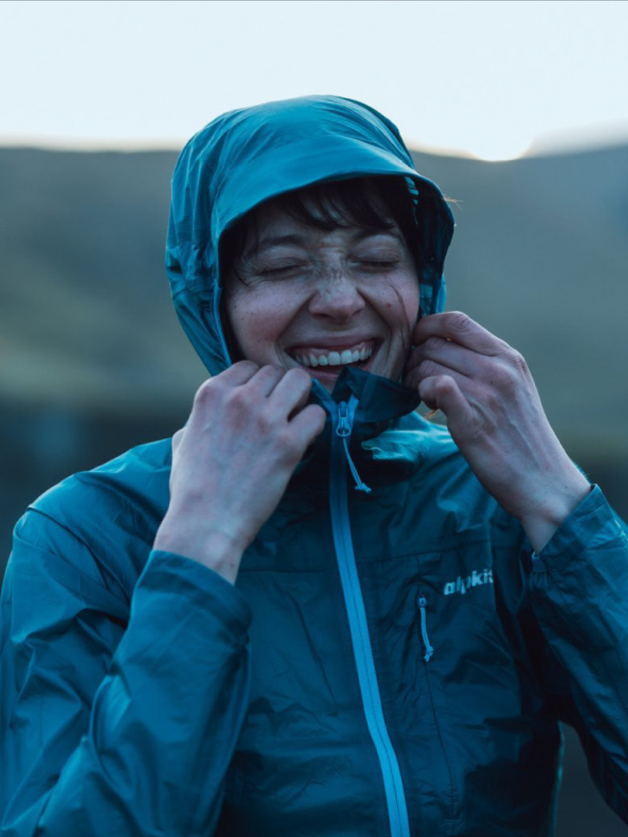 A photo of a woman laughing in a raincoat