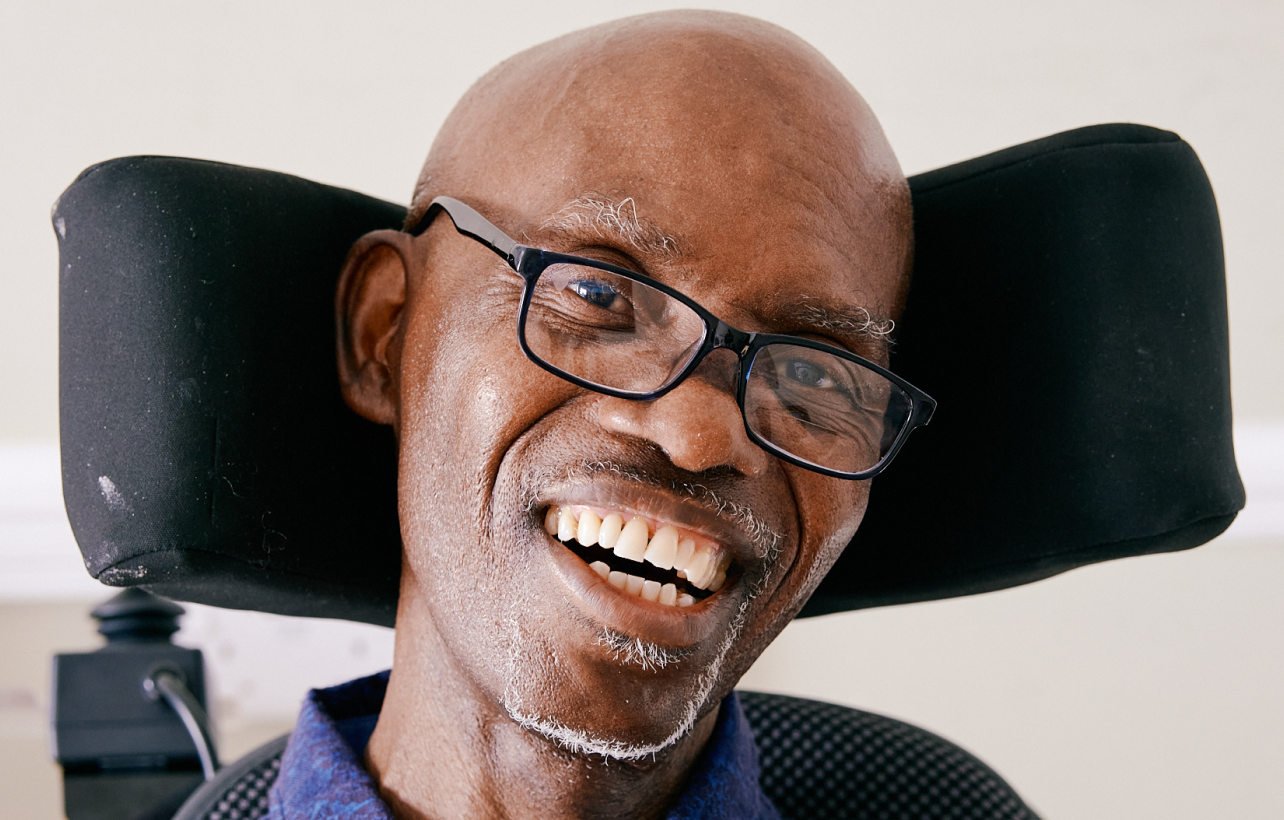 A man with MND wearing glasses in a wheelchair