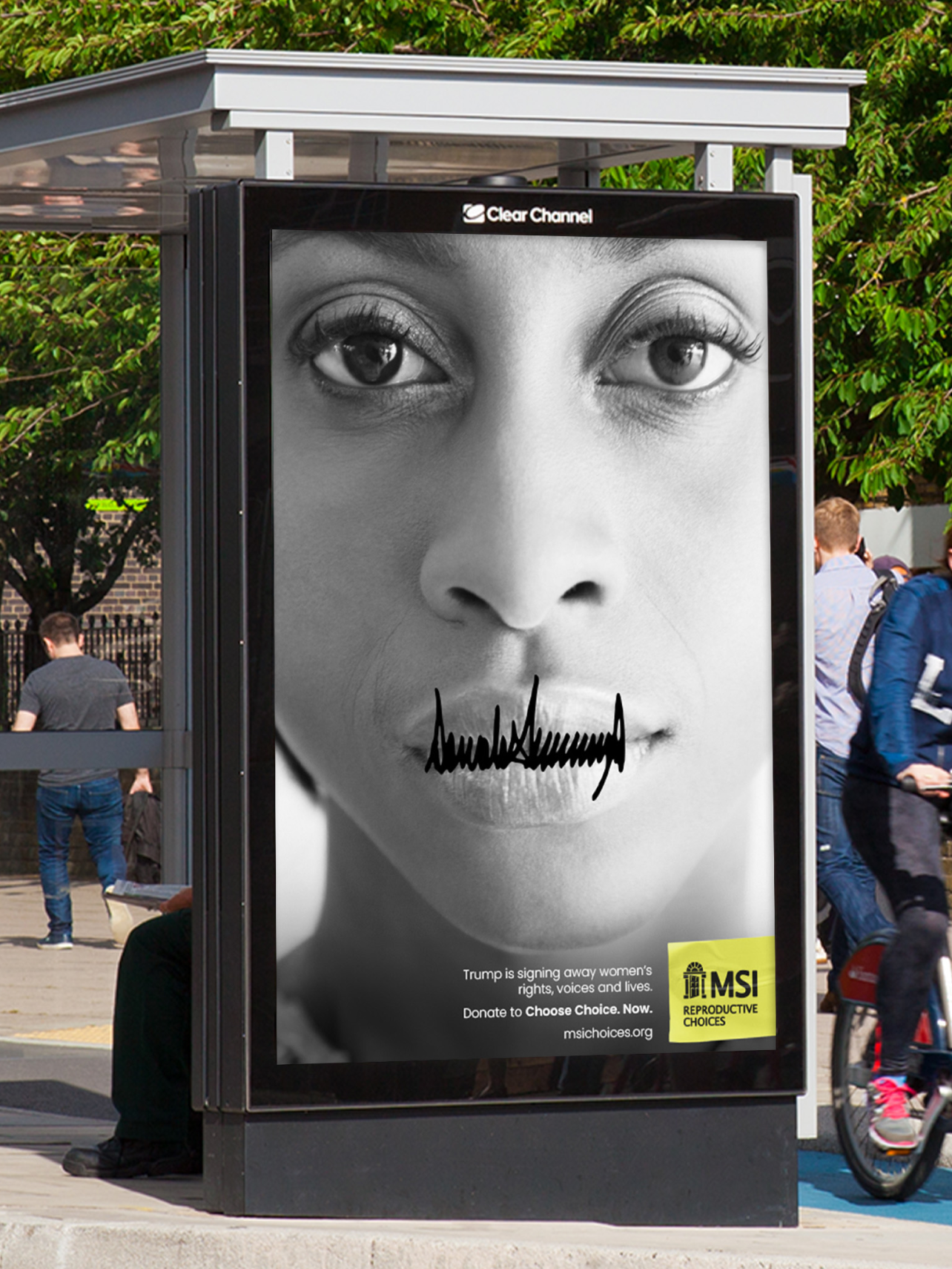 A photo of a digital poster at a bus stop of a woman's face with Donald Trumps signature over her mouth